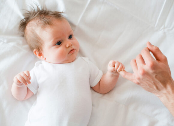 a_baby-lying-and-holding-little-finger-of-father